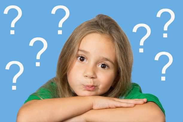 istock A child, a little girl with a pensive expression on her face, put her head on her folded hands, against the background of question marks. General educational concept. 1363595000