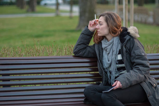 Depressed girl smoking on a bench stock photo