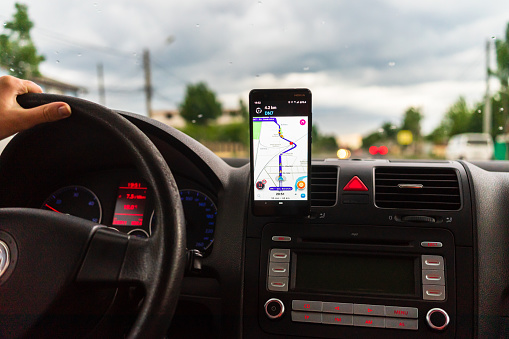 In car dashboard view with smartphone on Waze maps. Driver using Waze maps in Bucharest, Romania, 2022