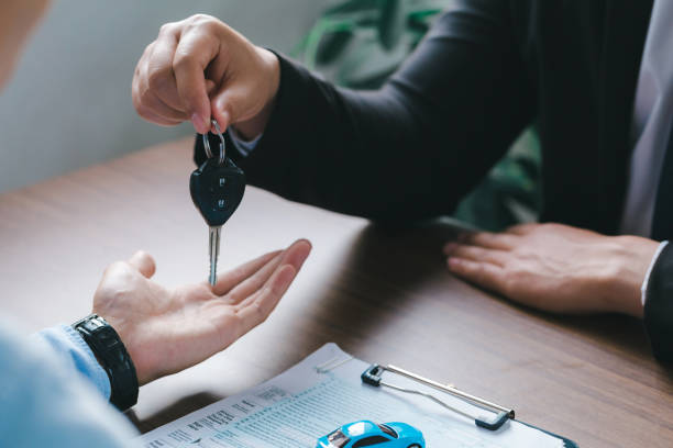 vue rapprochée main du vendeur de voitures donnant la clé de la voiture aux clients après avoir signé le contrat d’achat légalement, conclusion réussie des ventes de voitures, contrat d’achat, - car car rental car dealership key photos et images de collection