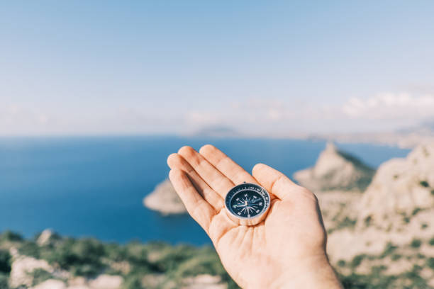istock Man holding a compass in the background sea and mountains. 1363596674