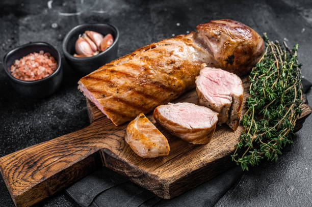 bbq roasted pork tenderloin fillet meat on wooden board with herbs. black background. top view - sirloin steak fotos imagens e fotografias de stock