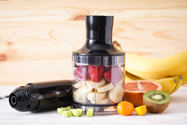 istock Hand blender and accessories with sliced fruit on a wooden background. Close up. 1363599525
