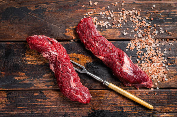 Uncooked raw Machete skirt steak on meat fork. Wooden background. Top view