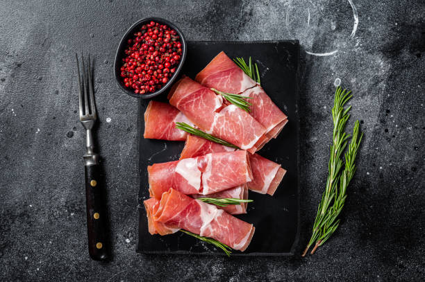 istock Traditional Spanish Jamon Serrano ham on marble board. Black background. Top view 1363600514