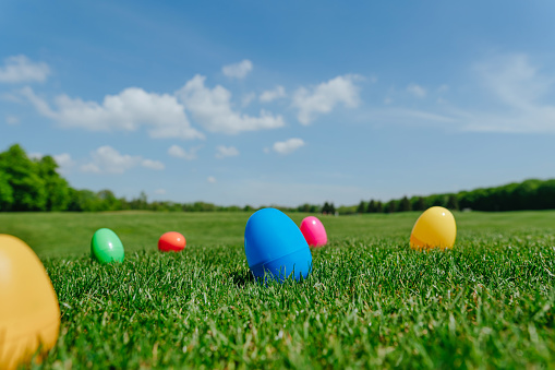 Colorful Easter eggs lying on the green grass outdoor. Easter holiday tradition for children of picking up the eggs. Selective focus.