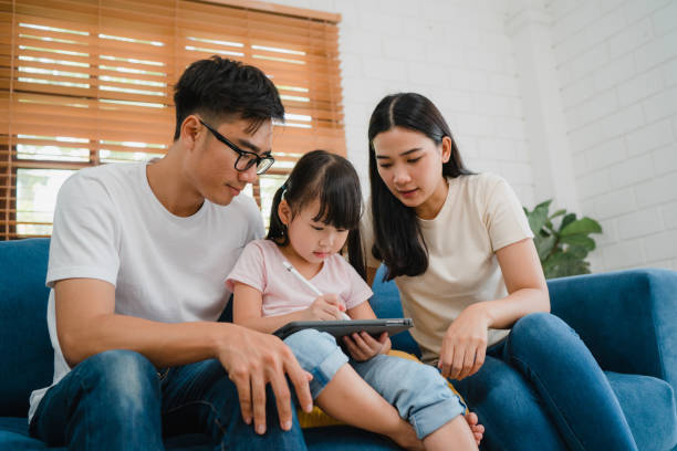 istock Happy Asian family dad, mom and daughter using computer tablet technology sitting sofa in living room at house. Self-isolation, stay at home, social distancing, quarantine for coronavirus prevention. 1363602078