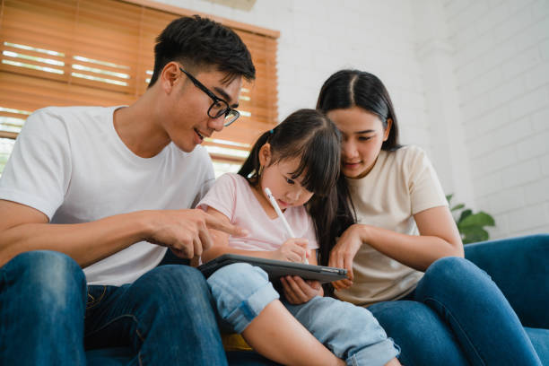 istock Happy Asian family dad, mom and daughter using computer tablet technology sitting sofa in living room at house. Self-isolation, stay at home, social distancing, quarantine for coronavirus prevention. 1363602098