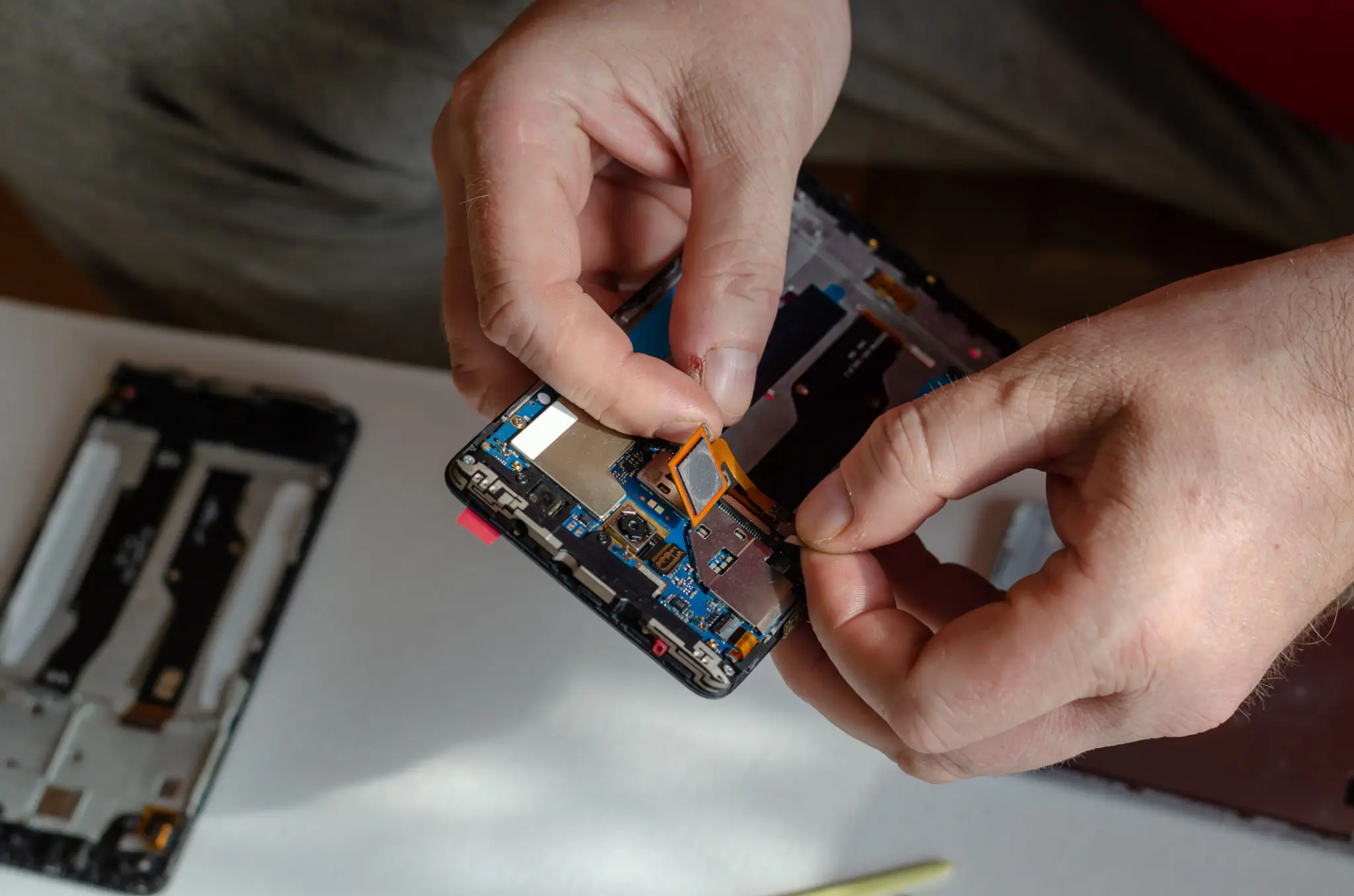 Repair of smartphones concept. A man uninstalls a fingerprint se