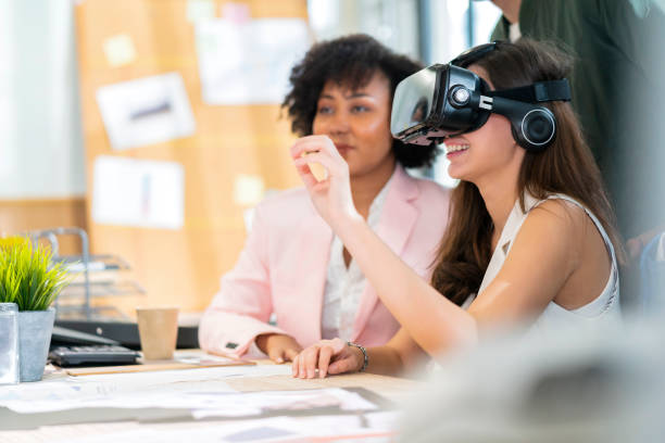 groupe de milléniaux masculin et féminin multiethnique utilisant des lunettes vr pour tester le système de réunion métavers joyeux et souriant, ami de bureau debout discussion ensemble à côté de l’arrière-plan du bureau de la fenêtre - réalité virtuelle photos et images de collection