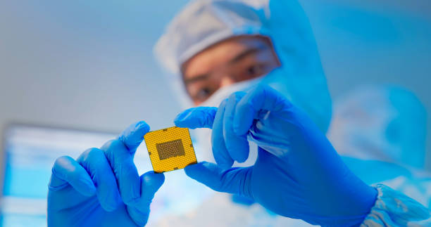 engineer holds microchip asian male design engineer in sterile coverall holds microchip with gloves and examines it - ultra modern electronic manufacturing factory rushes plant stock pictures, royalty-free photos & images