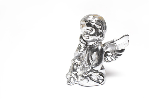 Close up of silver angel cast from clay on white background