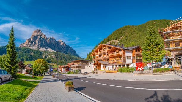 Panoramic view over magical Dolomite peaks, forests and hotels at sunny day and blue sky, Colfosco, Corvara, at Puez-Geisler, Puez-Odle Nature Park, South Tyrol, Italy