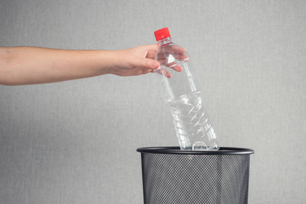 istock Woman throws pile of plastic bottles into mesh rubbish bin 1363611717