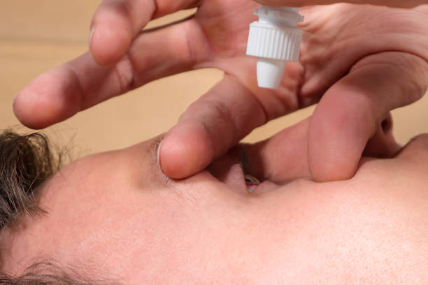 istock Man uses eye drops lying back on sofa in living room 1363611720