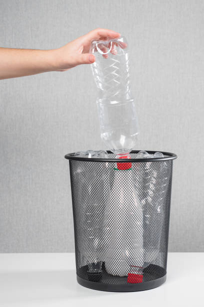 istock Woman throws pile of plastic bottles into mesh rubbish bin 1363611721