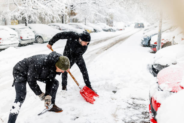 Two Friends are Solving the Problems with Snow Around Car Using Shovels. A Couple of Men is Using Snow Shovels to Clean up the Deep Snow in Front of Car. Shoveling Snow stock pictures, royalty-free photos & images