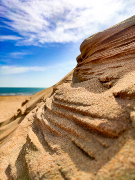 montagne de sable contre l’océan et un ciel bleu avec des nuages. dune dans le désert. une oasis sous le ciel - sahara desert coastline wind natural pattern photos et images de collection