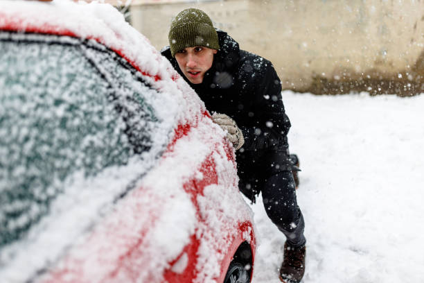 istock Man is Pushing a Car Stuck in Snow. 1363613826