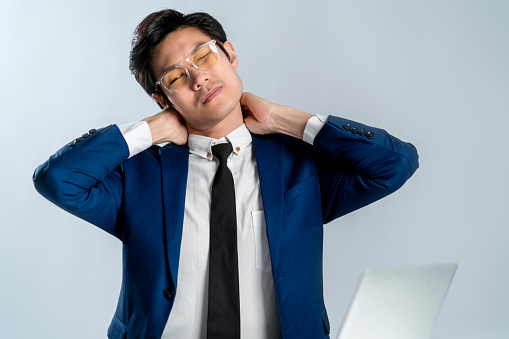 asian businessman wear formal suit sitting in office feeling body pain by office syndrome various symptoms including the inflammation of neck, shoulder and back muscles studio shot white background