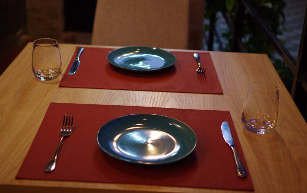 istock Green ceramic plate on red table mat with drinking glass and stainless steel fork and knife at restaurant outdoor area at night 1363616681
