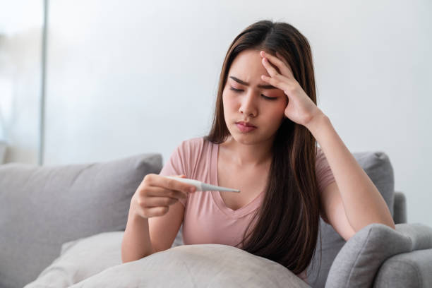 istock Asian young woman looking digital thermometer while she has a headache, a fever or for arthritis pain. 1363617421