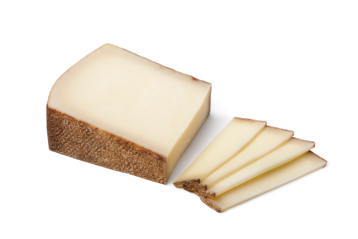 Piece of Swiss Gruyere cheese and slices on white background