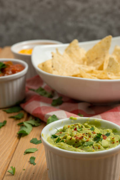 istock Bowls with red pepper sauce, cheddar and guacamole with nachos 1363619083