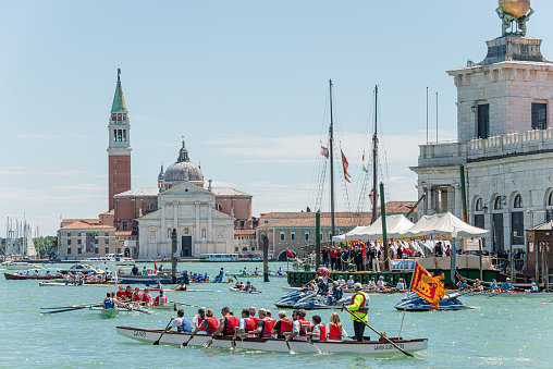 Venice, Italy - May 24, 2015: Annual Vogalonga Regatta, funny rowing racing in the Venetian Grand Canal around historical sightseeing like San Giorgio Maggiore Church and Basilica di Santa Maria della Salute.