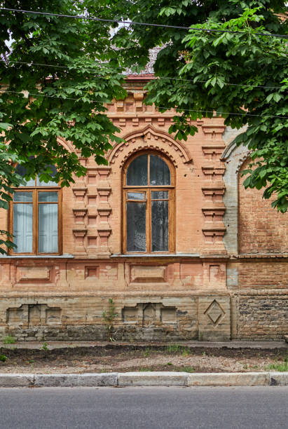 Wall of yellow building with arched windows on summer day