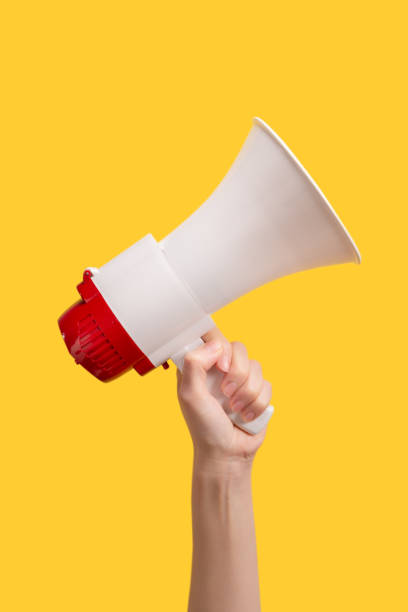 istock Megaphone in woman hands on a yellow background. 1363621015