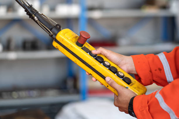 A worker is operating remote swtich to control overhead crane.