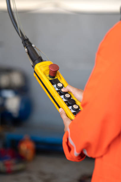 A worker is operating remote swtich to control overhead crane.