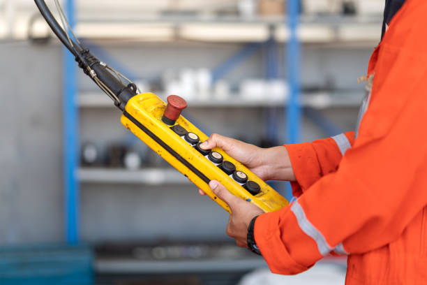 istock A worker is operating remote swtich to control overhead crane. 1363622714