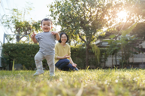 Portrait of Smiling Asian Little child son and his young mother in nature with sunlight, Happy family home concept.