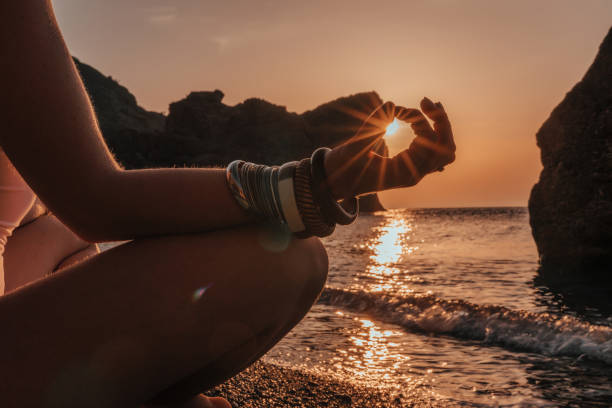 istock Young woman with long hair in white swimsuit and boho style braclets practicing outdoors on yoga mat by the sea on a sunset. Women's yoga fitness routine. Healthy lifestyle, harmony and meditation 1363629209
