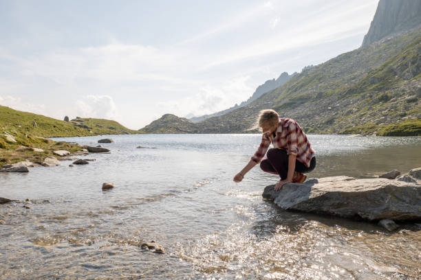 istock Young woman scooping water from alpine lake 1363629399