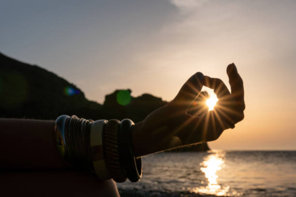 istock Young woman with long hair in white swimsuit and boho style braclets practicing outdoors on yoga mat by the sea on a sunset. Women's yoga fitness routine. Healthy lifestyle, harmony and meditation 1363629717