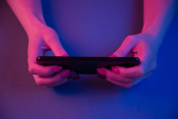 istock Woman hands using a cell phone in neon light. 1363629737