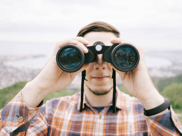istock Traveler young man looking through binoculars outdoor, front view. 1363629746