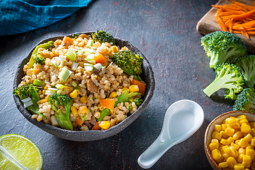 Stir fry brown rice vegan plant based asian recipe with ingredients as corn, soy sauce, chickpeas, garlic, red onion, carrot, broccoli, mushrooms, chili oil, black pepper