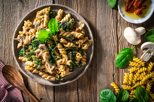 Fusilli with mushrooms Italian food vegan plant based recipe Mediterranean diet with ingredients as fusilli pasta, dried tomato, vegan cheese, shallots, garlic, chili, coconut milk, mushrooms, spinach, soy sauce, paprika