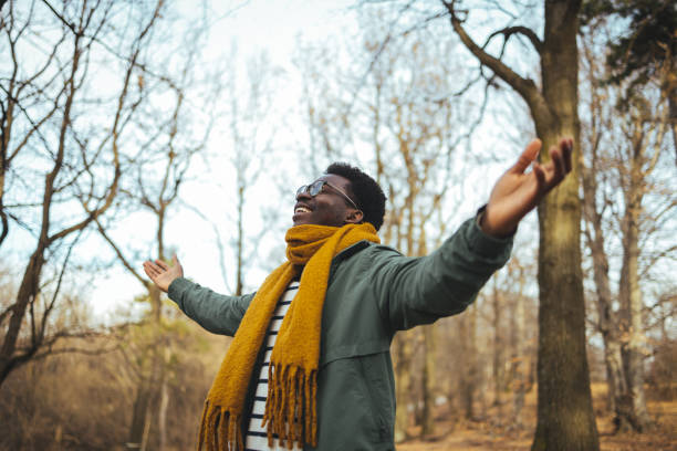 Black man breathing fresh air stretching arms in a park.