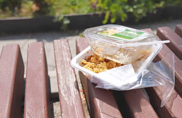 Photo of Leftovers food in disposable plastic package. Food left on a bench in plastic lunch boxes.