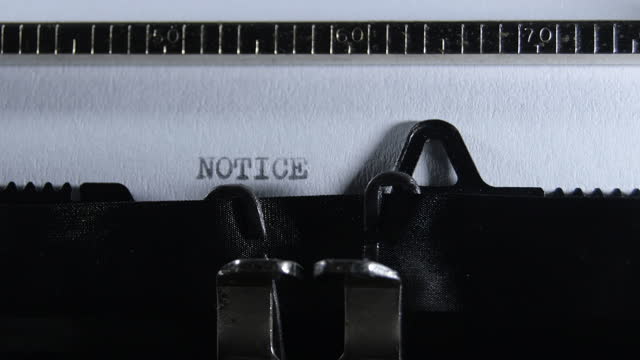 Typing the word NOTICE with an old manual typewriter