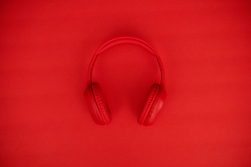 Cordless red headphones on a vibrant red background with copy space