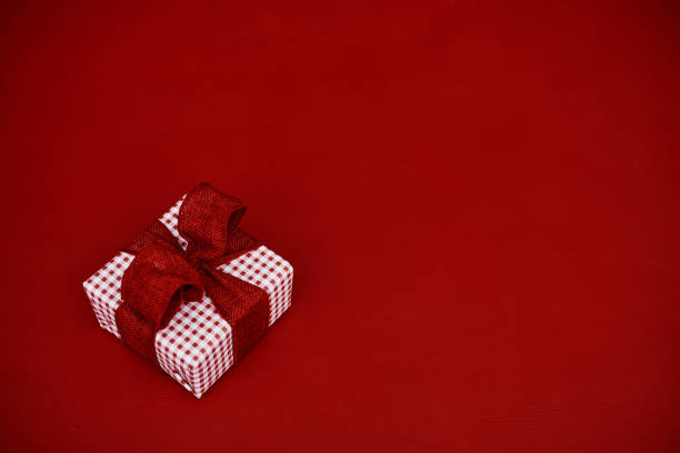 Gift wrapped with red ribbon on vibrant red background with copy space