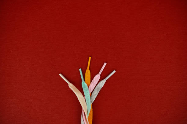 Colored shoelaces on a vibrant red background with space for copy
