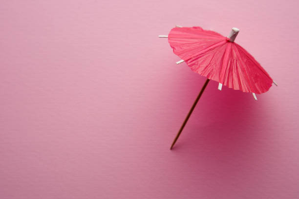 parapluie cocktail rouge isolé sur fond rose. - drink umbrella umbrella pink paper photos et images de collection