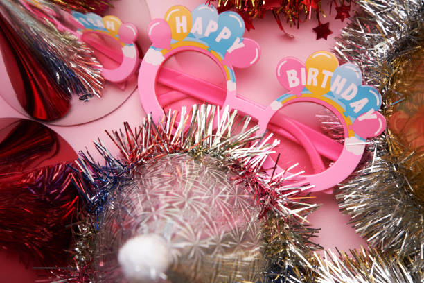 fancy birthday eyeglasses and party hats on pink background